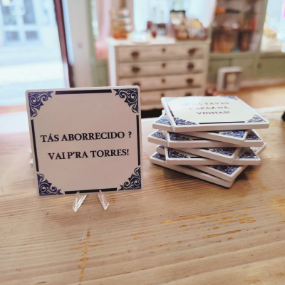 Azulejos quadrados brancos com texto em azul sobre suporte em madeira