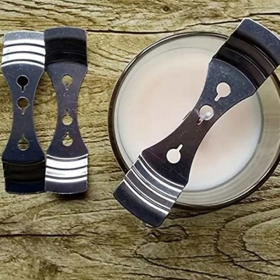 Clips metálicos prateados e pretos sobre madeira clara com tigela de líquido branco