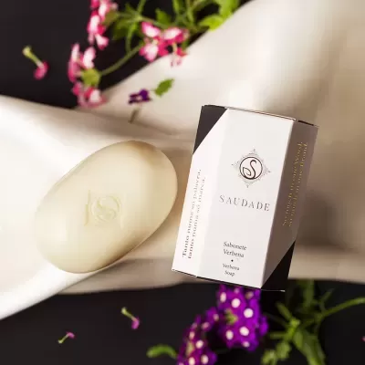Sabonete branco e embalagem branca com detalhes pretos e texto 'SAUDADE'