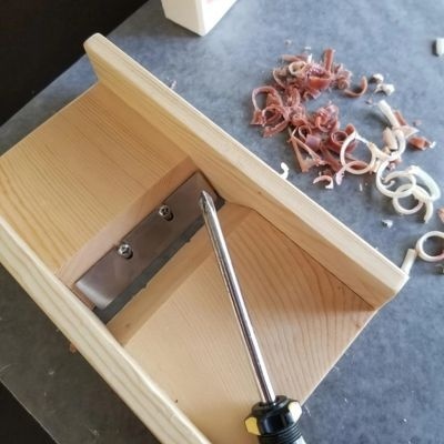 Planador manual de madeira com lâmina metálica e parafuso de ajuste com aparas de madeira