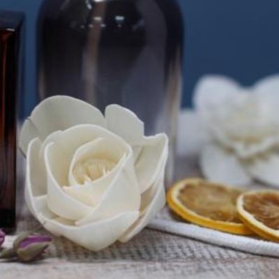 Flor branca artificial com frasco de vidro e fatias de laranja secas