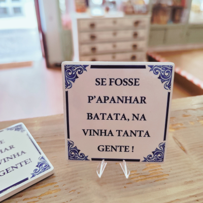 Azulejo cerâmico branco com padrão azul e texto em preto num balcão de madeira.