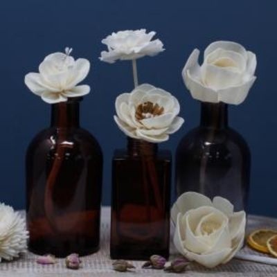 Frascos de vidro castanho com flores brancas sobre superfície clara e fundo azul