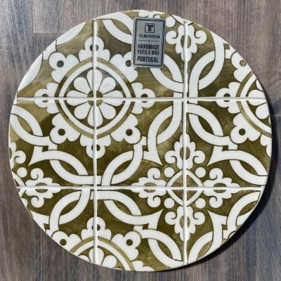 Prato redondo decorativo de azulejo com padrão branco e verde-oliva em superfície de madeira