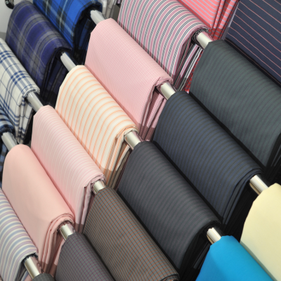 Rolos de tecido coloridos com padrões listrados e xadrez em suportes metálicos