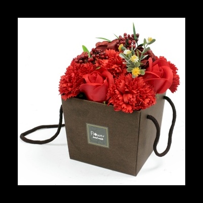 Arranjo floral decorativo numa caixa castanha com flores vermelhas artificiais