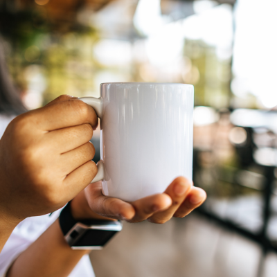 Caneca branca de cerâmica segurada por mão com relógio