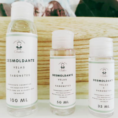 Três frascos transparentes de líquido com rótulos brancos e texto preto, em diferentes tamanhos, sobre uma superfície de madeira.