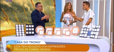 Azulejos decorativos com expressões típicas de Torres Vedras numa banca em estúdio de televisão com três apresentadores