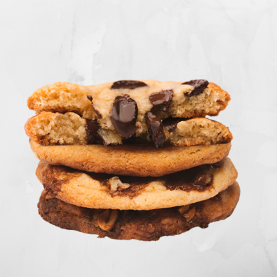 Conjunto de três bolachas de chocolate empilhadas, a superior partida ao meio com pedaços visíveis.