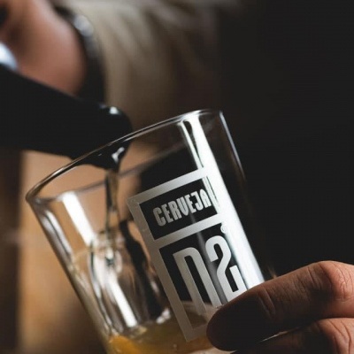 Copo transparente com texto 'CERVEJA 02' sendo enchido com cerveja dourada