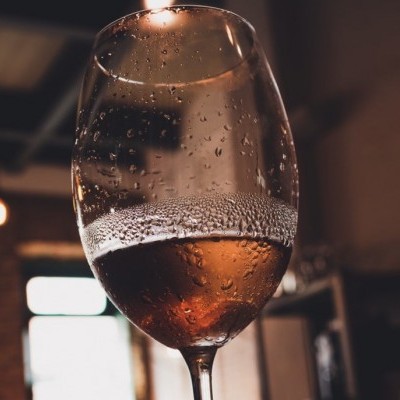 Taça de vidro com líquido rosado e gotas de condensação