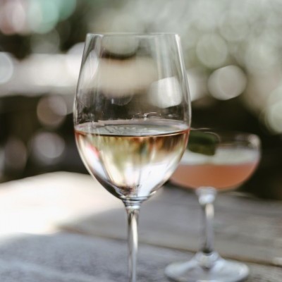 Copo de vinho branco e copo de cocktail desfocado no fundo