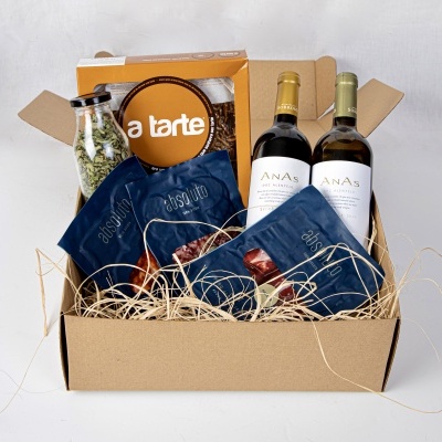 caixa de cartão aberta com vinho, pacotes de alimento, garrafa de ervas e caixa de tarte