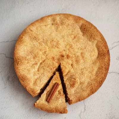 Tarte redonda dourada com fatia cortada e pau de canela