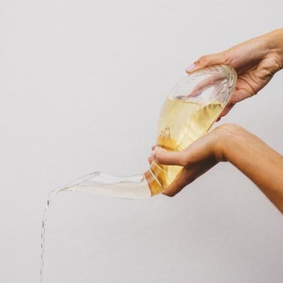 Mãos a deitar líquido de vaso de vidro transparente com bico fino