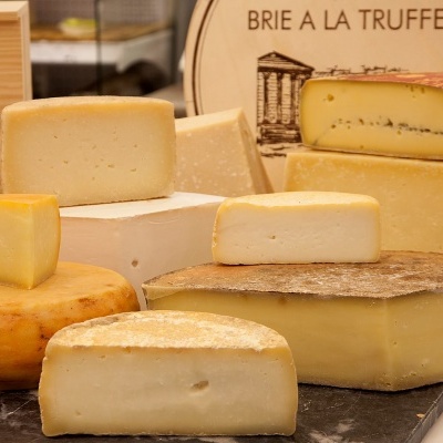 Vários queijos de diferentes tipos e uma tábua redonda com texto BRIE A LA TRUFFE