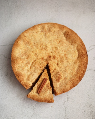 Tarte redonda dourada com fatia cortada e pau de canela