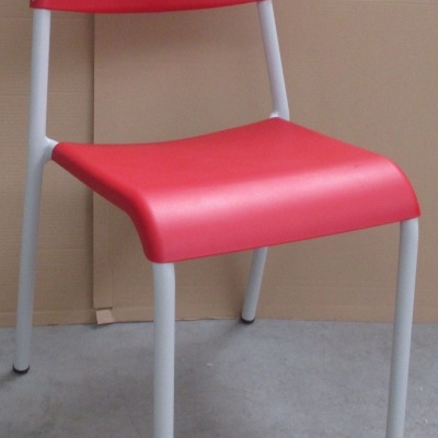 Cadeira vermelha com estrutura metálica branca em chão de cimento