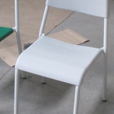 Cadeira branca de plástico e metal em chão de cimento com caixas de cartão ao fundo