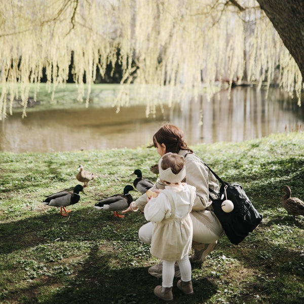 PORTA-CHUCHAS DE SILICONE | MUSHIE Mãe e filha alimentando patos perto de um lago com árvores ao fundo