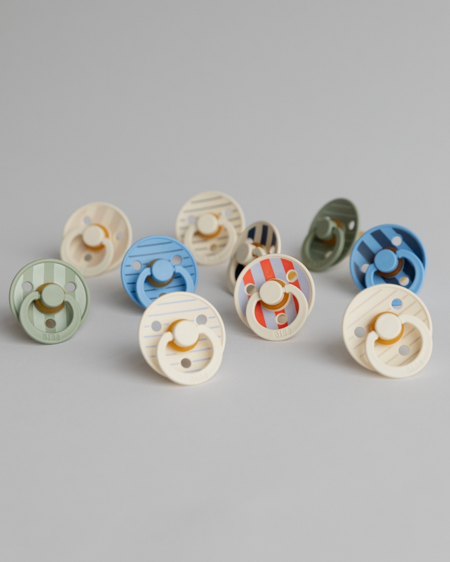 BIBS COLOUR | STUDIO EDITION Conjunto de chupetas coloridas com padrões de riscas sobre fundo cinzento