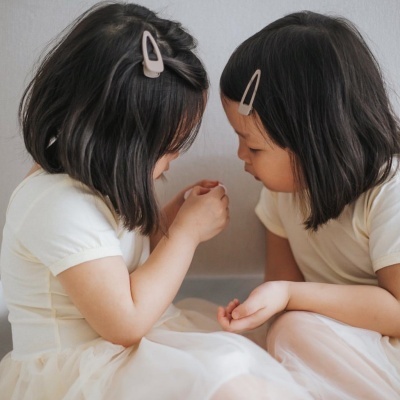 Duas meninas pequenas com vestidos brancos sentadas lado a lado