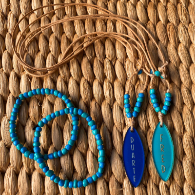 Conjunto de bijuterias com colares de contas azuis e pendentes ovais com nomes DUARTE e FRED