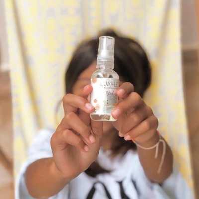 Frasco de spray LUAS E LÁ segurado por pessoa