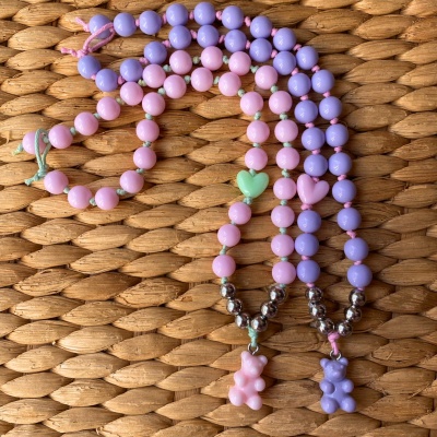 Colares coloridos com pingentes em forma de ursinho sobre esteira de palha