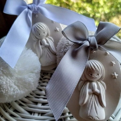 Decorações com anjos em relevo, laços azuis e cinza e pompons brancos