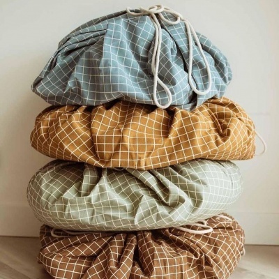 Almofadas redondas empilhadas em azul, mostarda, verde claro e castanho com padrão de quadrícula branca.