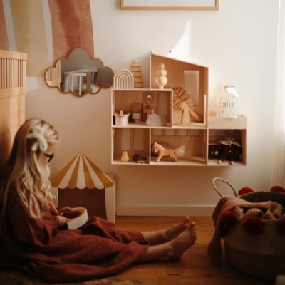 Estante de brinquedos infantil em madeira clara com brinquedos e espelho decorativo