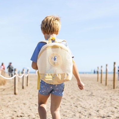 Mochila infantil amarela com bolso de rede numa praia