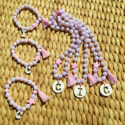 Pulseiras e colares de contas rosa e lilás com letras, estrelas e franjas cor de rosa
