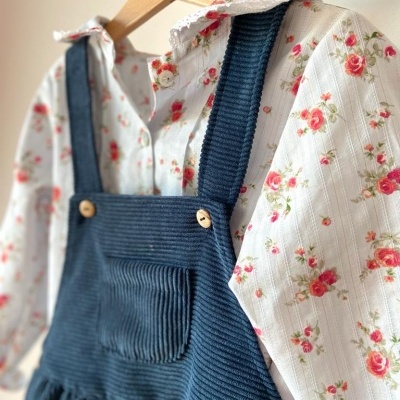 Vestido azul de cotelê com camisa branca floral pendurados em cabides