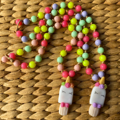 Colar colorido com pendente de gelado unicórnio sobre superfície trançada castanha