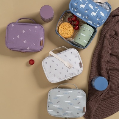 Quatro lancheiras de tecido coloridas, recipientes e roupas em fundo bege