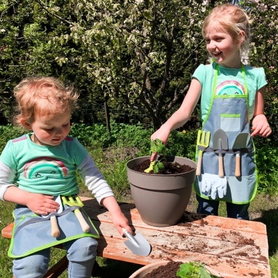 Crianças a fazer jardinagem com aventais e ferramentas ao ar livre
