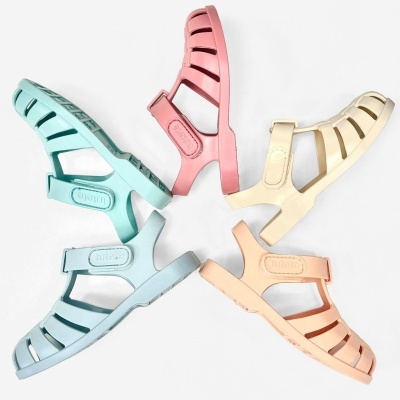 Quatro sandálias plásticas tipo gladiador em azul claro, rosa, amarelo e pêssego, dispostas em círculo