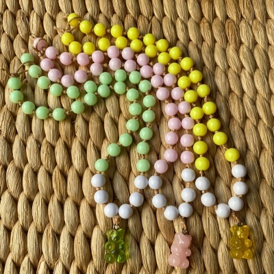 Quatro colares coloridos com pendentes de ursinho de gelatina sobre superfície trançada