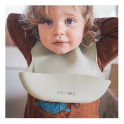 Criança com babete de silicone bege e camiseta castanha