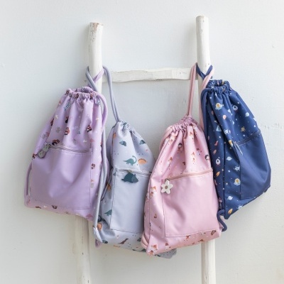 Quatro mochilas de tecido coloridas com padrões florais penduradas numa escada branca