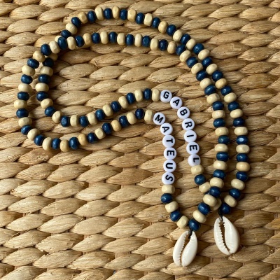 Colar com contas azuis e bege, nomes em contas brancas, pingentes de búzios em fundo de fibra trançada