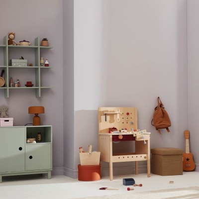 Espaço interior com banca de madeira infantil e móvel verde claro