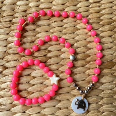 Conjunto de colar e pulseira de contas cor de rosa com símbolos sobre fundo de vime