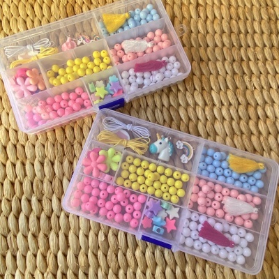 Caixas transparentes com miçangas coloridas e acessórios em cima de superfície de fibras naturais entrelaçadas.