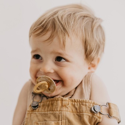 Criança com babygrow castanho claro e chucha translúcida acastanhada