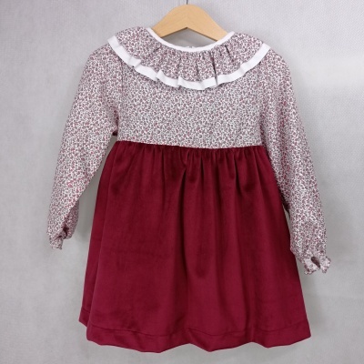 Vestido infantil com parte superior floral e saia vermelha, pendurado num cabide