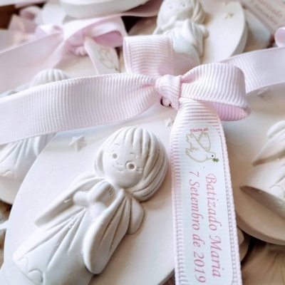 Placa de cerâmica branca com anjo e fita rosa com texto sobre batizado